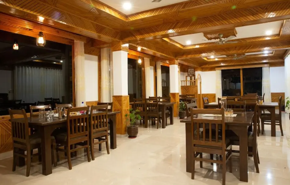 Dining hall at Shree Ganga Cottages Restaurant and Bar with wooden interiors
